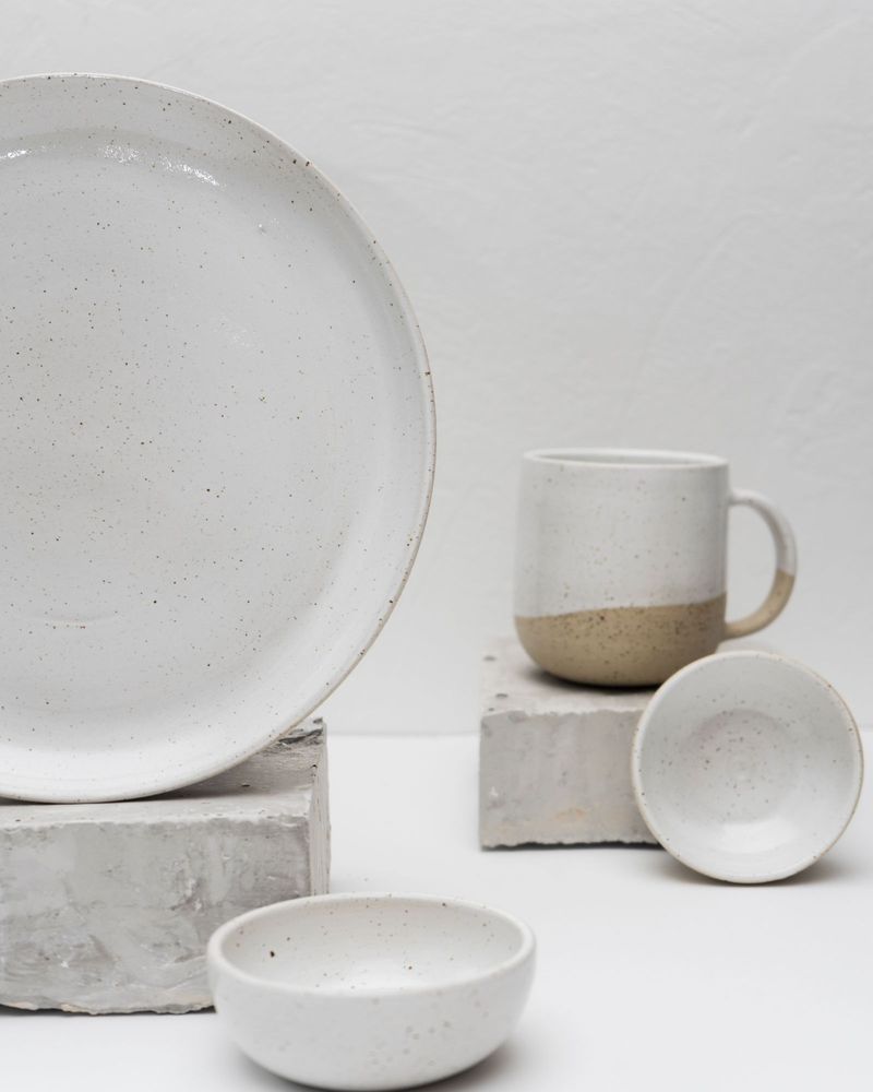 A speckled two-tone ceramic mug with matching bowls